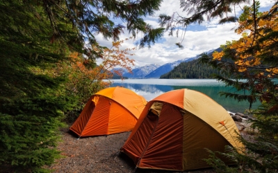 Two colorful tents set up near a pristine mountain lake and forest